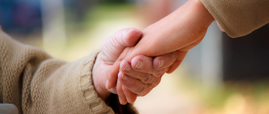 A caregiver holding a senior's hand.