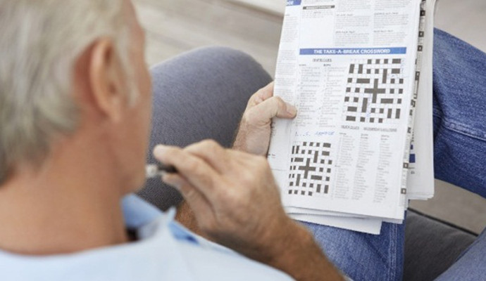 A senior man doing a newspaper crossword puzzle.